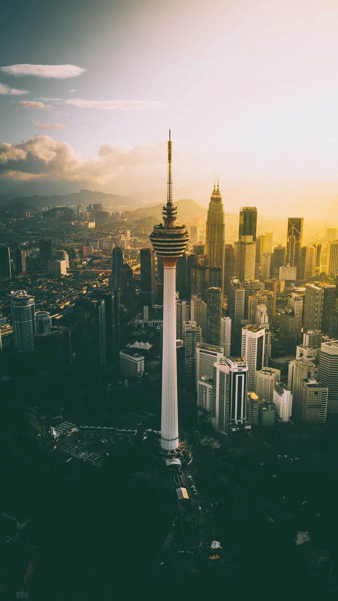 Luftbild von Kuala Lumpur mit dem Fernsehturm Menara KL und den Petronas Towers im goldenen Gegenlicht