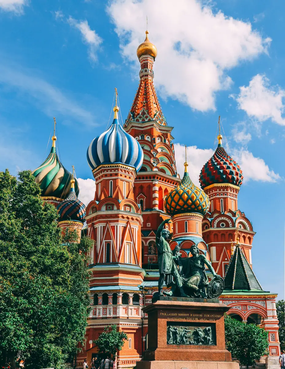 Bunte Zwiebeltürme der Basilius-Kathedrale in Moskau mit dem Denkmal für Minin und Poscharski im Vordergrund.