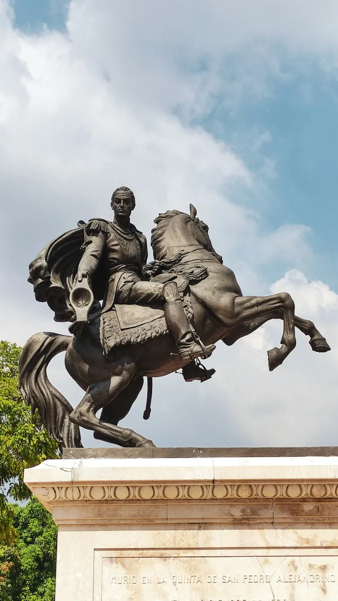Bronzenes Reiterstandbild von Simón Bolívar auf einem steigenden Pferd über einem Marmorsockel mit Inschrift.