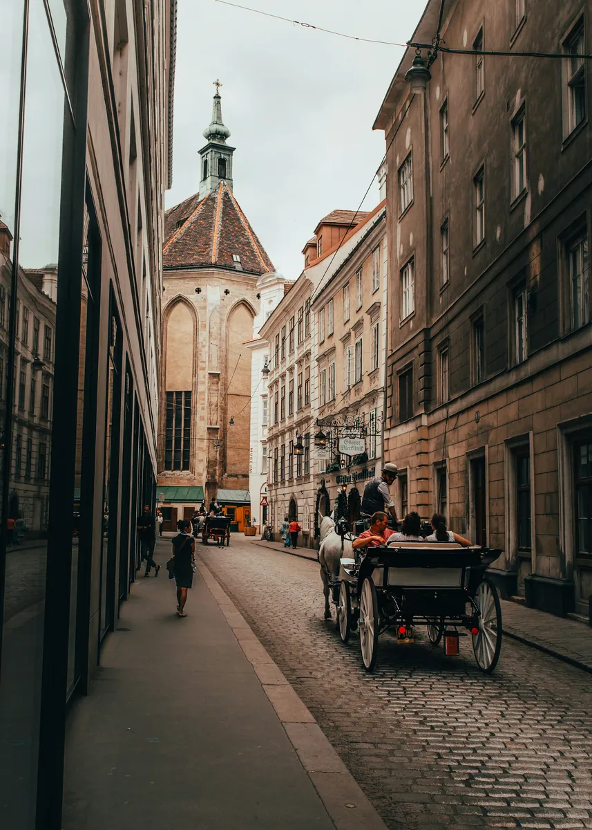 Pferdekutsche mit Fahrgästen auf einer kopfsteingepflasterten Altstadtgasse, im Hintergrund der gotische Giebel einer Kirche